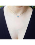 1.01 ct blue sapphire bezel set on a 14K gold cable chain choker necklace worn by a woman.