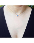 1.01 ct blue sapphire bezel set on a 14K gold cable chain choker necklace worn by a woman.