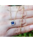 1.01 ct blue sapphire choker necklace, bezel set in 14K gold, on a hand.