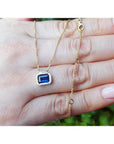 1.01 ct blue sapphire choker necklace, bezel set in 14K gold, on a hand.