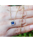 1.01 ct blue sapphire choker necklace, bezel set in 14K gold, on a hand.