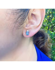 14K yellow gold earrings with medium-light blue sapphire and diamond accents on an ear.