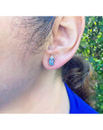 14K yellow gold earrings with medium-light blue sapphire and diamond accents on an ear.