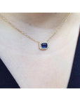 1.03 ct. emerald-cut blue sapphire necklace with diamond halo on a 14K yellow gold chain.