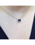 1.03 ct. emerald-cut blue sapphire necklace with diamond halo on a 14K yellow gold chain.