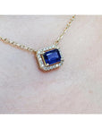 1.03 ct. natural blue sapphire, emerald cut, east-west necklace with diamond halo in 14K yellow gold.