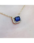 1.03 ct. natural blue sapphire, emerald cut, east-west necklace with diamond halo in 14K yellow gold.