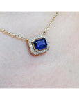 1.03 ct. natural blue sapphire, emerald cut, east-west necklace with diamond halo in 14K yellow gold.