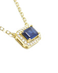 Right side profile, gallery exposed of a natural blue sapphire necklace emerald cut halo diamonds in 14k yellow gold.