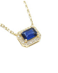 Right side top view of a natural blue sapphire necklace emerald cut halo diamonds in 14k yellow gold.
