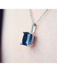 Necklace with a pendant featuring a blue sapphire gemstone on a person's neck.