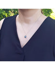 Woman wearing a 4.11 ct cushion cut deep blue sapphire solitaire pendant on a 14K white gold chain.