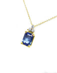 14k gold necklace with an emerald-cut blue sapphire pendant and three diamond accents.