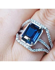 18k white gold ring with a natural blue sapphire certified gemstone untreated in an emerald cut ,held on a finger.