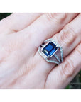 18K gold ring with a 4.51 ct emerald cut blue sapphire and a three-row diamond band.