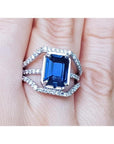 18K gold ring with a 4.51 ct emerald cut blue sapphire and a three-row diamond band.