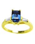 Women's blue sapphires ring rich medium-dark hue, flanked by side tapered baguette diamonds in 14k yellow gold.