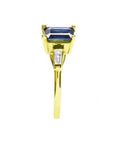 14K yellow gold ring with a rectangular emerald-cut blue sapphire and tapered baguette diamonds.