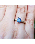 Gold ring with a blue natural sapphire on a person's finger