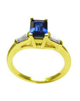 1.13 ct. emerald-cut blue sapphire ring with tapered diamonds in 14K yellow gold.