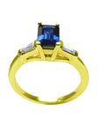 1.13 ct. emerald-cut blue sapphire ring with tapered diamonds in 14K yellow gold.