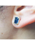 Close-up of a blue sapphire gemstone earring on an ear