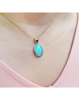Opal pendant necklace on a person's neck wearing a pink top.