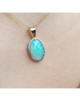 Opal pendant necklace on a gold chain against a skin background.