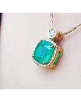 Cushion-cut Colombian emerald necklace with halo diamonds in 18K yellow gold.