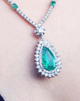 Green teardrop emerald pendant with double halo of diamond accents on a Leidy's neck