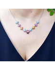 18K white gold necklace with tri-colored topaz X-cluster links on a woman's neck.