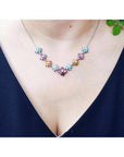 18K white gold necklace with tri-colored topaz X-cluster links on a woman's neck.