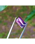 Purple tourmaline held between tweezers with a blurred green background