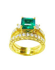 Gold ring with a natural emerald and diamonds wedding band match on a white background.