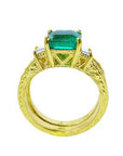 A lateral view of a natural emerald ring bridal style, top setting, gallery and band ring visibles.