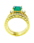 Lateral profile view of a bridal wedding band with diamonds in front of the main emerald ring.