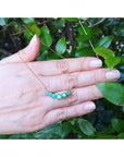 14K gold necklace with five round, medium green Colombian emeralds in elegant basket settings.