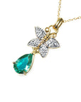 Gold necklace with a colombian teardrop emerald and butterfly pendant on a left-side position, topside visible.