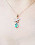 Necklace with a natural emerald teardrop pendant and butterfly design on a plain skin background.
