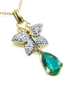 Gold butterfly pendant with natural teardrop emerald and diamond accents on a right position topside view.