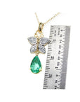 14K gold butterfly pendant with pavé diamonds and a pear-shaped Colombian emerald, shown with ruler.