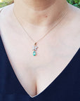 Necklace with a butterfly emerald pendant worn by a person against a blurred natural background.