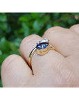 On a finger a Two-stone "You and Me" blue natural sapphire bypass ring handcrafted in 18k yellow gold.