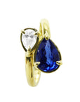 A bypass 18k yellow gold you and me ring toi et moi design featuring a natural pear-cut blue sapphire and a smaller diamond.