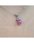 Pink natural sapphire cabochon and diamond necklace on a person's neck.