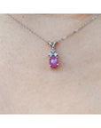 Pink cabochon sapphire pendant on a white gold chain against a skin background.