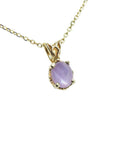 Natural oval-cut cabochon pink sapphire pendant necklace with a medium sparkle hue, set in prongs within a 14k yellow gold scroll design.