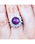 Red purple cabochon star ruby women's ring front top view in a double halo natural diamonds on a hand