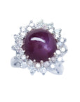 Women's 18K white gold ring with a purple cabochon star ruby and double halo diamonds.