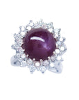 Women's 18K white gold ring with a purple cabochon star ruby and double halo diamonds.